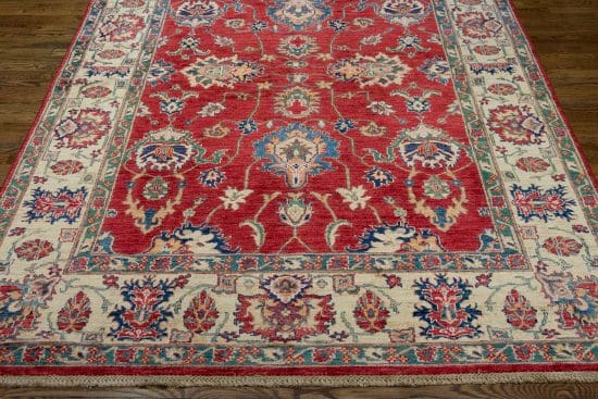 A floral-geometric handmade wool Kazak style rug in red and beige colors. Size 6x9.